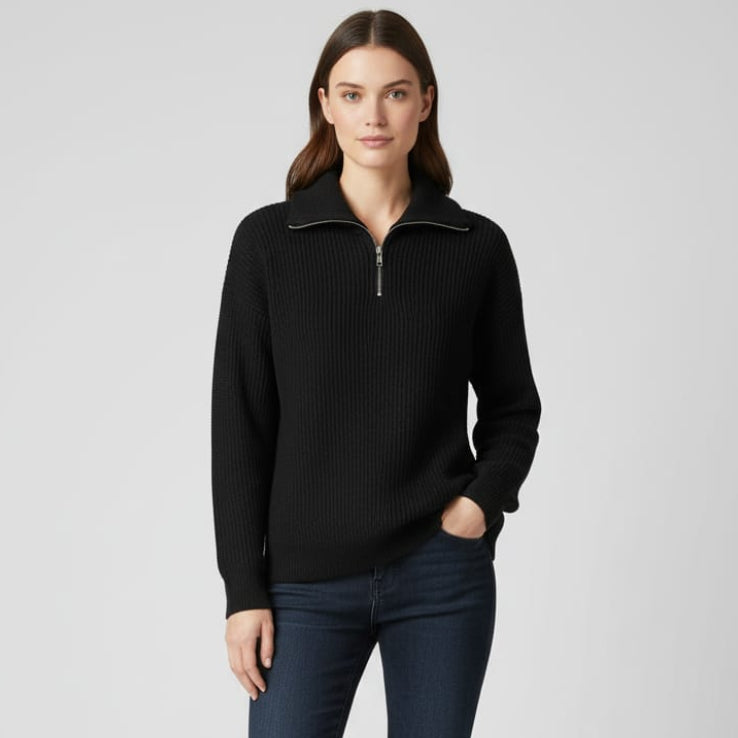 Woman wearing a black zip-up sweater and dark jeans on a white background